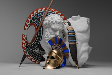 Shot of greek bust with body and weapons of soldier against gray background.