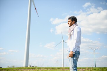 Indian Engeenier standing against windmills