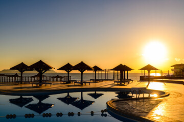 View on a swimming pool in hotel resort and Red Sea at sunset