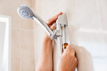 A master plumber installs a shower head in the bathroom. 