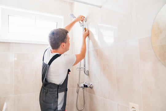 A master plumber installs a shower head in the bathroom. 