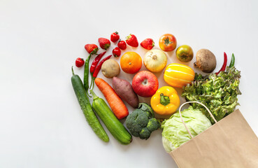 Healthy food background with assortment of fresh organic vegetables and fruits. Grocery shopping concept with shopping bag isolated on white background. Top view.
