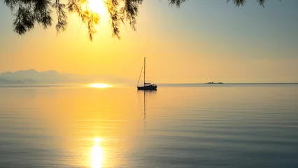 Fototapeten Early morning on calm sea, orange sky and sailing yacht, calmness, serenity and meditation © HAYRULLAH