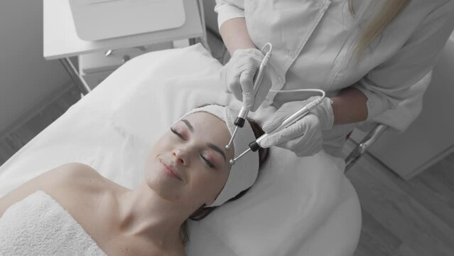 Beautiful woman at dermatology treatment center undergoing microcurrent procedure which helps improve facial skin condition and reduce signs fatigue. Rest and relaxation at reception at cosmetologist