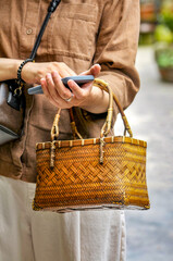 a chinese woman using smartphone and holding fashion bamboo bag