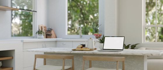 A laptop mockup on a modern kitchen island or kitchen counter in a modern white kitchen