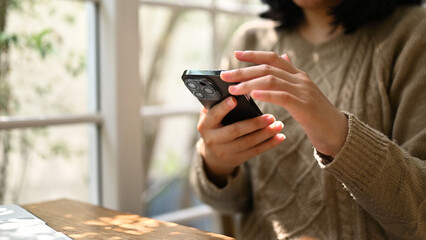 A woman using her smartphone, scrolling on her phone while relaxing at a cafe.