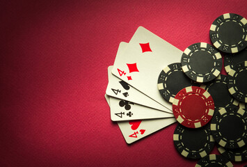 Poker game with a winning combination of four of a kind or quads. Cards with chips on a red table in a poker club.