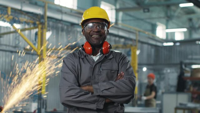 Worker of a technical enterprise in a work uniform is sincerely smiling and satisfied. The plant engineer smiles confidently. Satisfied locksmith is happy with the work done