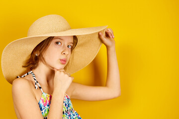 Child teenager girl in swimsuit and straw hat posing