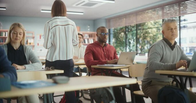 Adult Education Center: Diverse Mature Students Learning in Classroom, Using Laptops and Writing in Notebooks. Group of People Taking a Workshop on Improving Professional Work Skills