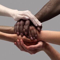 Support and care. Human hands of different race, skin color holding together over grey background. Humanity. Acceptance. Concept of human relation, community, togetherness, symbolism, culture - obrazy, fototapety, plakaty