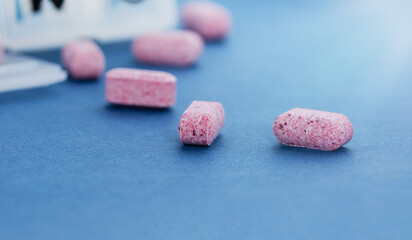 Conceptual image of a pill organizer with pills scattered on a blue table.