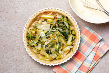 Cooking quiche with leek, chicory, egg, cheese and cream. Raw, unbaked butter pie crust, homemade...