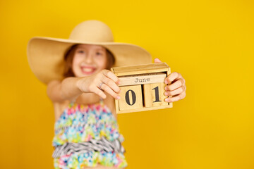 Child teenager girl in swimsuit and straw hat hold in hand wooden calendar