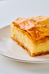 close up of a piece of galaktoboureko on a white plate