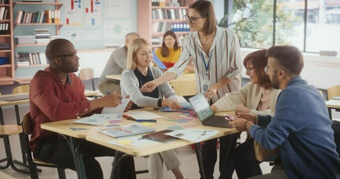 Adult Education Center: Adult Students Learning in Classroom, Working as as Two Teams on a Verbal Education Game. Positive Female Teacher Giving Advice, Answering Questions and Motivating Students