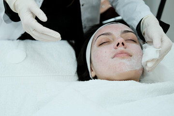 Cosmetologist cleaning woman's face before applying face treatments . Preparing patient's skin before treatment. 