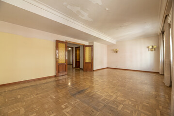 A large empty room in a house with parquet floors, several windows with curtains