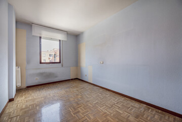 An empty room with damask parquet flooring with red aluminum window and soft white blind