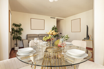 Beautiful glass dining table with tableware set and a full fruit bowl