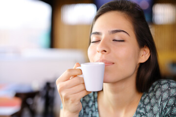 Woman smelling coffee cup in a restaurant