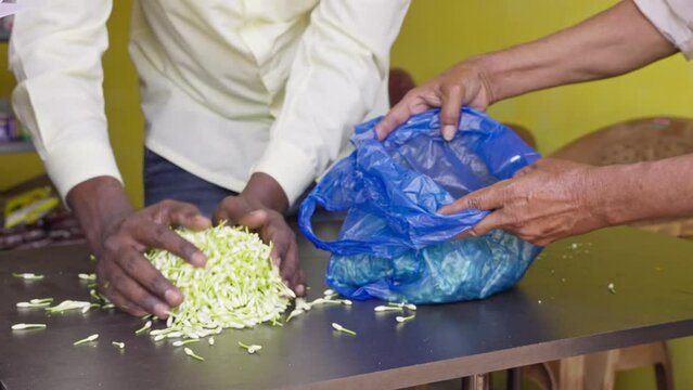 Closeup of hands filling fresh jasmine flower buds in plastic bags in the shop