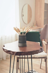 live edge wooden slab coffee table with cement vase and wheat stems. vertical shot of cozy place in home.