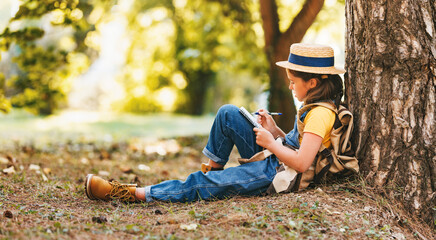 child girl  takes notes in a notebook while walking through   forest