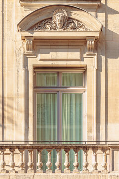 Fenêtre avec fronton sculpté et petit balcon d'une façade d'immeuble haussmannien à Paris