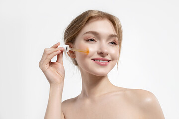 Beautiful smiling woman  with perfect skin applying moisturizing facial serum.