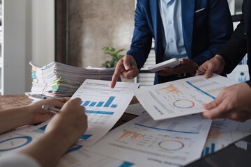 Business team using a calculator to calculate the numbers of statistic business profits growth rate on documents graph data, desk in the office, teamwork process