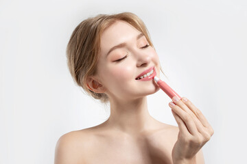 Portrait of gorgeous smiling woman holding rosy lipstick in hand.  Beauty and cosmetics concept.