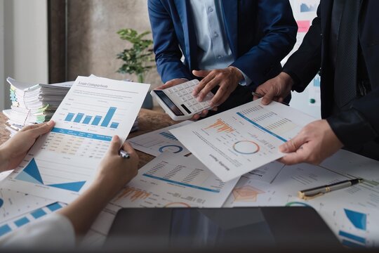 Business team using a calculator to calculate the numbers of statistic business profits growth rate on documents graph data, desk in the office, teamwork process