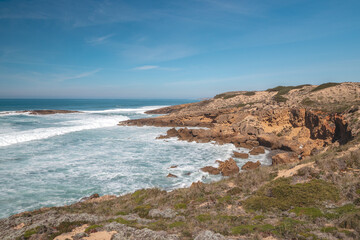 Fototapeta na wymiar Mountainous and unstable rocky scenery at Atlantic Coast on a sunny day in the Odemira region, western Portugal. Wandering along the Fisherman Trail, Rota Vicentina