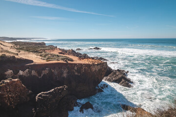 Fototapeta na wymiar Mountainous and unstable rocky scenery at Atlantic Coast on a sunny day in the Odemira region, western Portugal. Wandering along the Fisherman Trail, Rota Vicentina