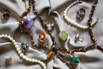 Many different silver rings and necklace with various natural gemstones over background. - obrazy, fototapety, plakaty