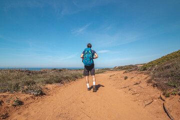 Explorer and hiker walk across the sandy terrain towards his destination in the Odemira region, western Portugal. Wandering along the Fisherman Trail, Rota Vicentina