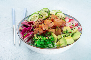 Tuna poke bowl with avocado, cucumbers, wakame, radish, and purple cabbage, a healthy Hawaiian dish, with chopsticks