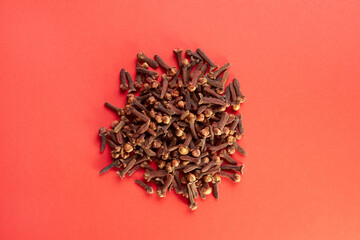 Heaps of spices cloves on a red background.