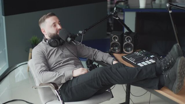 A handsome radio host speaks into a microphone during a radio broadcast.