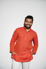 Indian man smiling while standing with hands in pockets isolated over white background