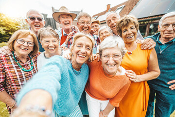 Happy group of senior people smiling at camera outdoors - Older friends taking selfie pic with smart mobile phone device - Life style concept with pensioners having fun together on summer holiday - obrazy, fototapety, plakaty