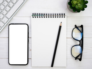 Workplace with blank notepad, pencil, glasses and smartphone. Mockup. Flatlay. Top view. Copy space.