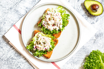step-by-step preparation of a sandwich with tuna, avocado, cucumber and onion