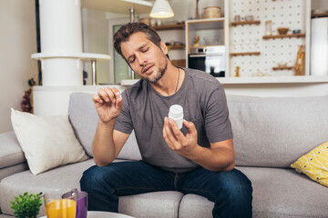 Handsome young man taking pill at home