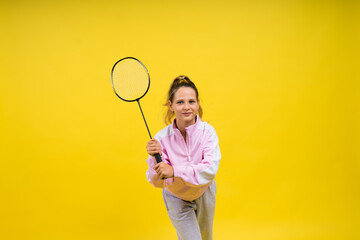 Full length studio photo of ten year old girl holding badminton racket and isolated on yellow.