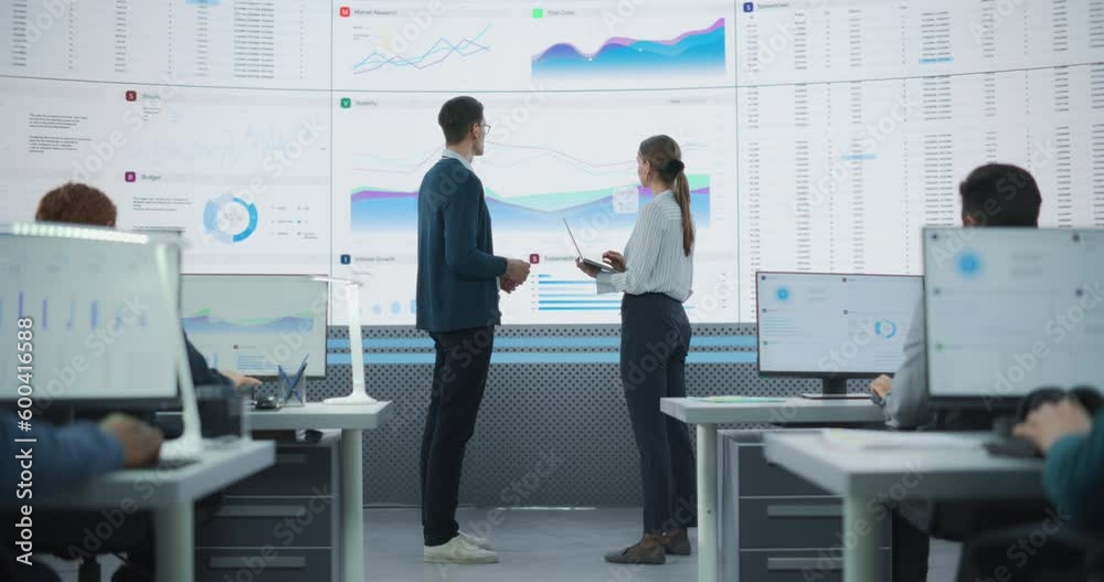 Aufkleber zoom out back view shot of male and female analysts discussing financial data on big digital screen 