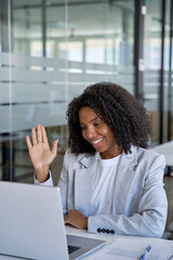Vertical portrait of African American businesswoman waving hand making video call at webcam on laptop in office for remote work at job. Young woman have online business conference lesson training.