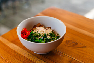 Delicious noodles with herbs and mushrooms in a white plate. Delicious business lunch on the veranda in summer.